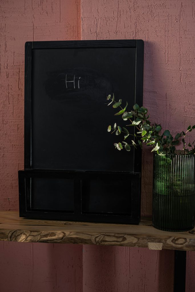 A vertical shot of a small chalkboard with 'Hi' written, adorned with a decorative plant.