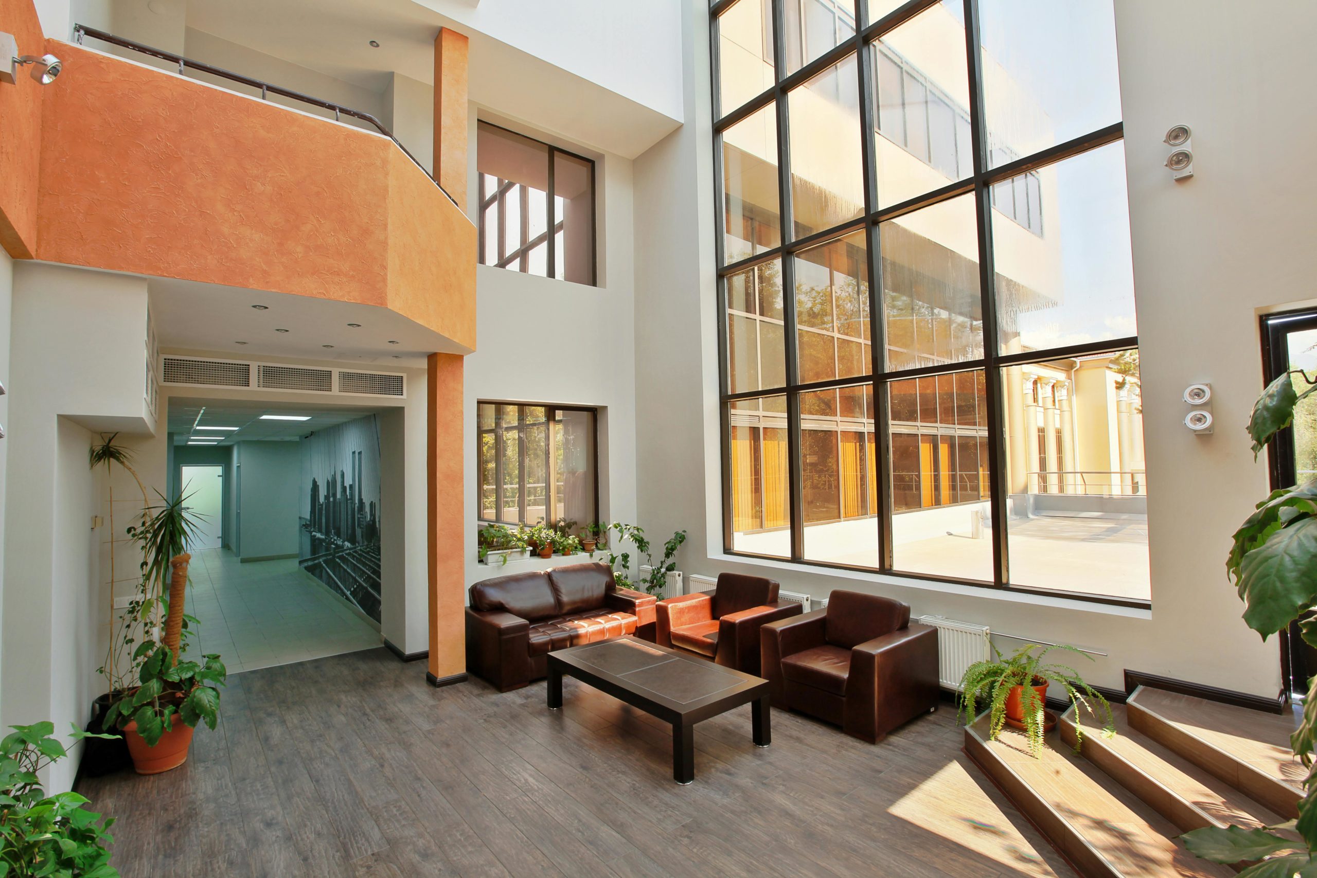 A spacious, modern lobby with high ceilings, large windows, and contemporary furniture.